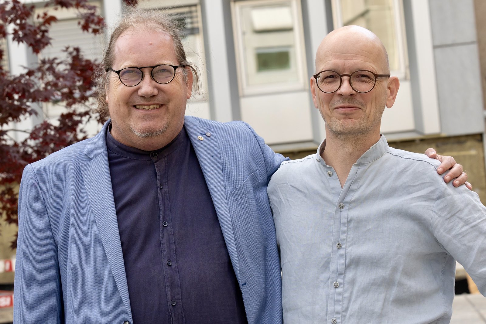 Zwei Männer mit Brille lachen in die Kamera